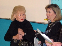 Eleanor Mauer (left) confers with an auction attendee while watching the event.