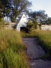 Small building with 3 foot high doors. Holds parts of a lawnmower. 